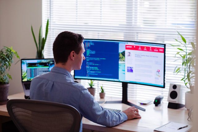 A man in a blue dress shirt working to develop a website