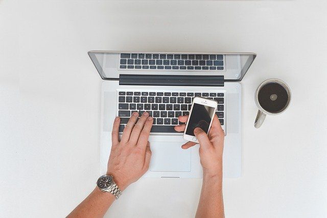 A person checking their phone and laptop