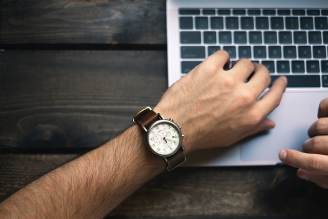 man's hands with watch and laptop