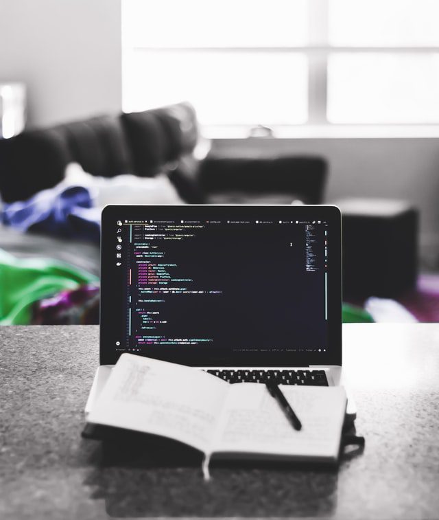 A notebook on top of a laptop with code on the screen