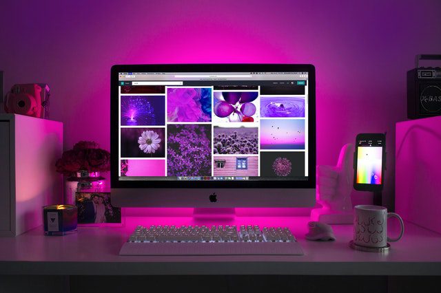 A silver desktop computer on a white desk displaying a collage of images