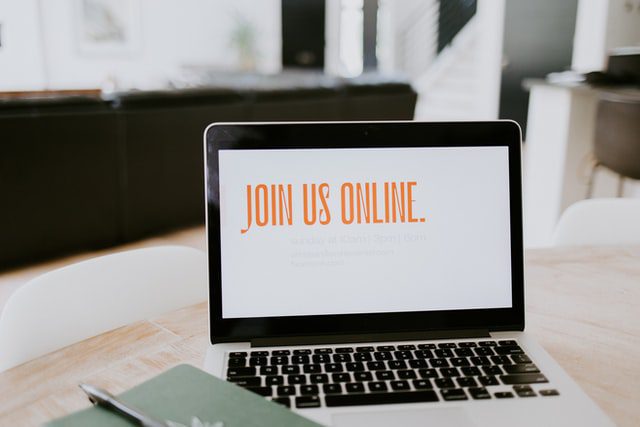 A silver laptop displaying the text “join us online”