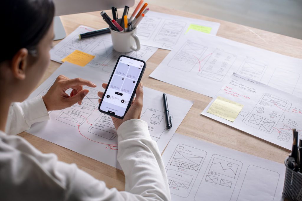 UI/UX testing - person holding a mobile device in front of mockups