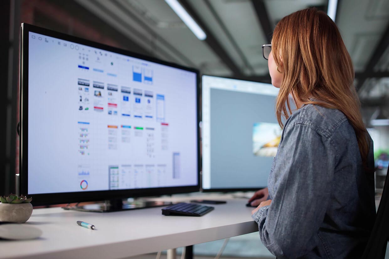 Female looking at 2 computer monitors