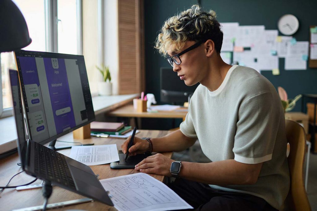 Male seated around a desk with 1 computers and several printouts