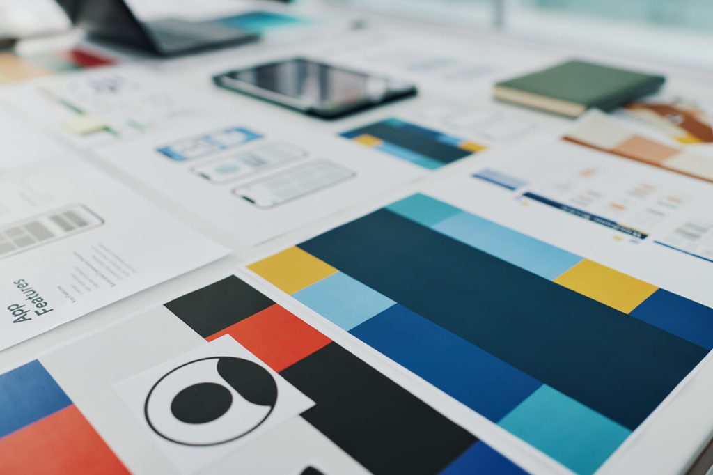 Desk with charts, mockups, laptop, and book