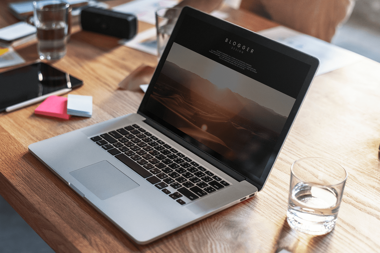 Desk with glass with water and a Laptop screen with Blogger display