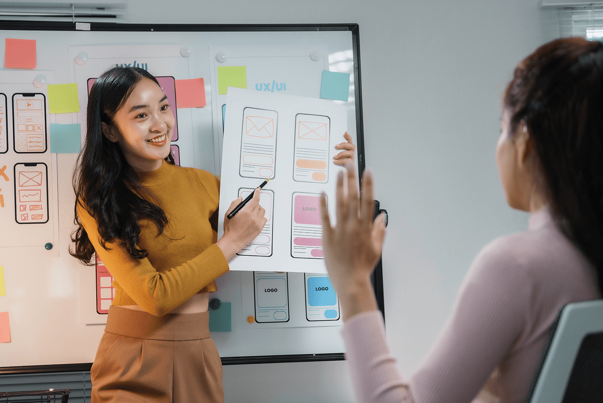 Female standing at a white board with paper mockups
