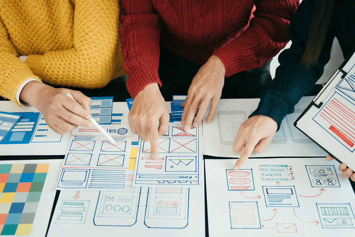 Several hands pointing to mockups on a table