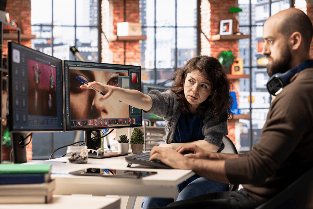 Woman pointing to a screen seated beside a man typing on a keyboard