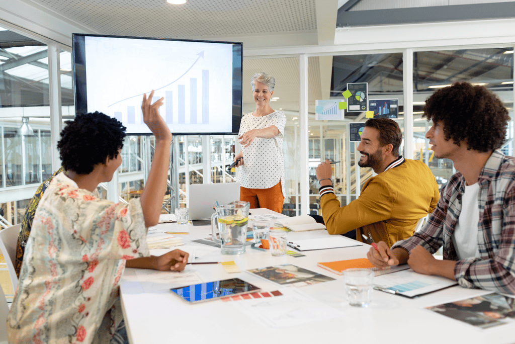Group of people around a desk with a screen with bar graph