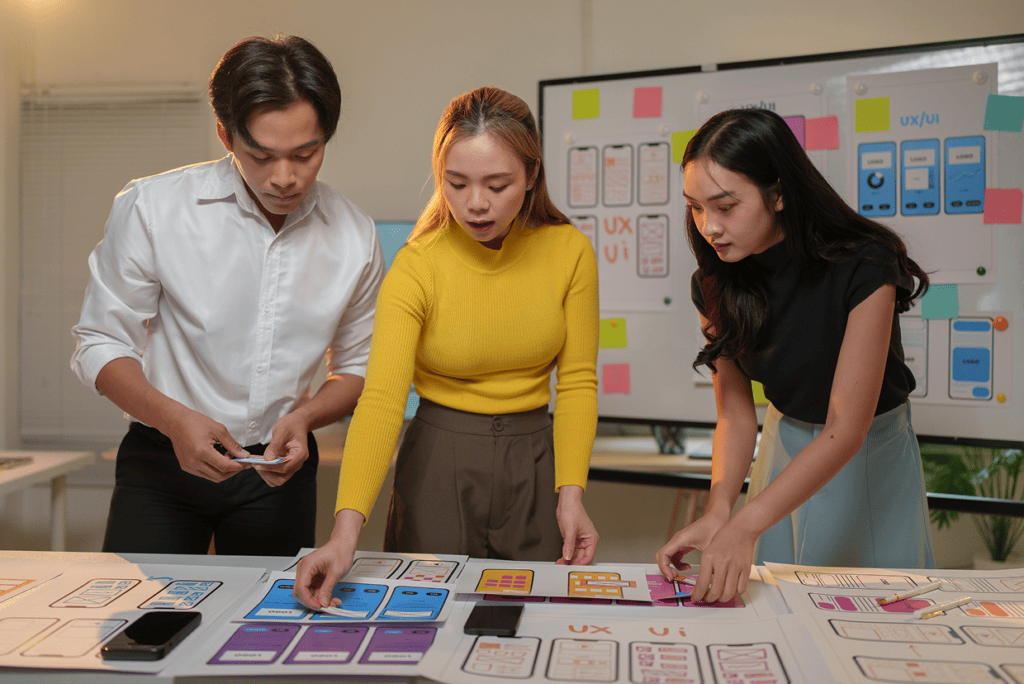 3 persons looking at a des with multiple mockups