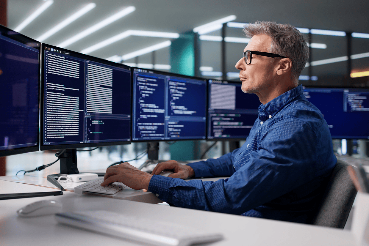 Male in blue long sleeved shirt looking at a monitor with codes